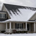 How much snow can a roof hold shown on a steep pitched asphalt shingle home with snow shedding off the upper roof slope