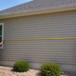How to Measure a Roof for Shingles (2026) How to measure a roof for shingles shown with two people measuring an exterior wall length with a tape measure
